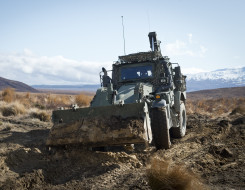 A green New Zealand Army High Mobility Engineer Excavator (Combat Tractor) moves dirt around in the Waiouru Military Training Area