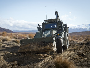 A green New Zealand Army High Mobility Engineer Excavator (Combat Tractor) moves dirt around in the Waiouru Military Training Area