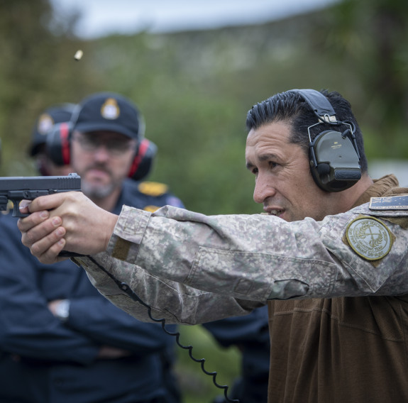 A New Zealand Army soldier fires a Glock G17 Gen 4 with other NZDF personnel watching on in the background. These personnel are out of focus. 