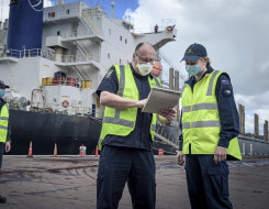 NZDF personnel working with NZ Customs personnel with a ship in the background