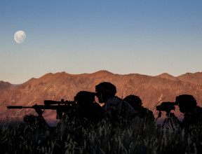 New Zealand Army soldiers using the Designated Marksman Weapon (DMW). The soldiers are silhouetted with the mountain range in the background lit up