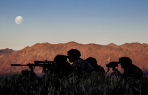 New Zealand Army soldiers using the Designated Marksman Weapon (DMW). The soldiers are silhouetted with the mountain range in the background lit up