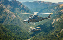 Two A109 helicopters fly over the mountain range. 