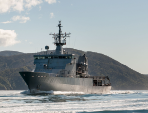 HMNZS Wellington sailing through the Marlborough Sounds, in the background y