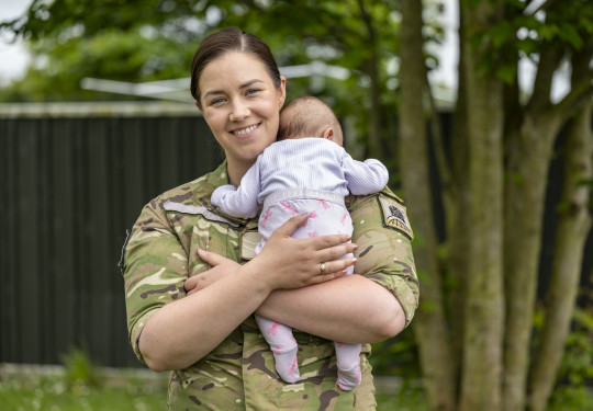 A woman in NZ Army uniform holds her baby.