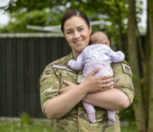 A woman in NZ Army uniform holds her baby.