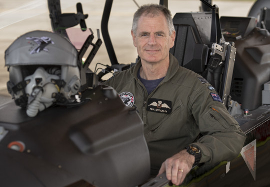 RNZAF Aviator sits in the cockpit of an aircraft staring at the camera. 