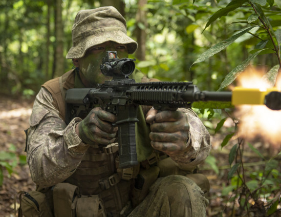 A New Zealand Army Reservist wearing camo paint fires a weapon on Bersama Lima.