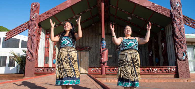 Members of Te Taua Moana Marae performing in front of the marae in cultural dress.