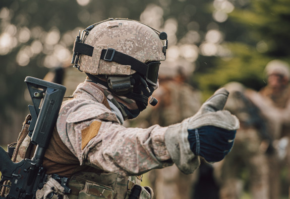 A New Zealand Army soldier wearing full kit including a mask and goggles gives a thumbs up