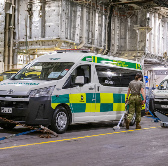 Inside HMNZS Canterbury two ambulances are secured in place in a line.