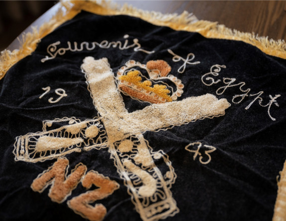 Photo of an embroidered flag from 1943, featuring the letters 'NZ", and crown and the year it was made.