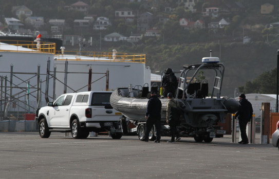 A RHIB attached to a white utility vehicle is prepared to be launched in an industrial area.