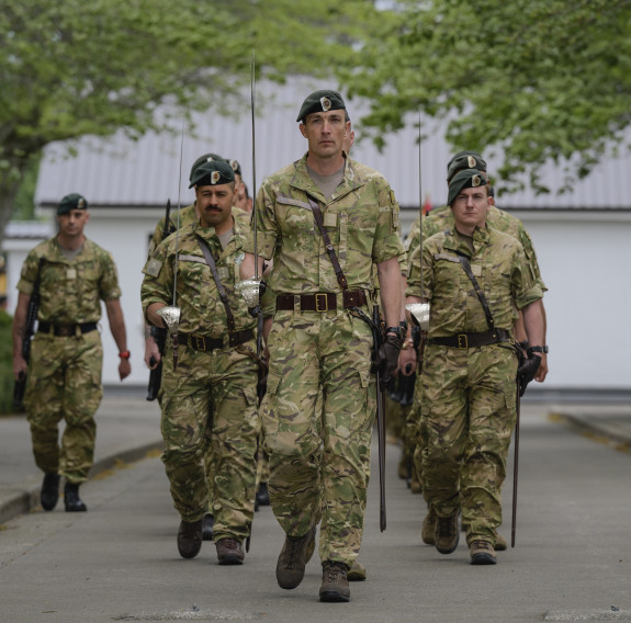 Soldiers march down a street towards the camera.